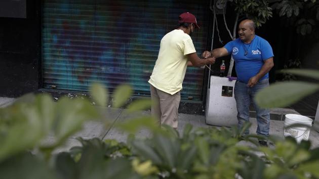 A man pauses from his work to give a tip to Arturo Lezama, whose nephews were playing a marimba on the street outside, in the Roma Norte neighborhood of Mexico City. (AP Photo/Rebecca Blackwell) A man pauses from his work to give a tip to Arturo Lezama, whose nephews were playing a marimba on the street outside, in the Roma Norte neighborhood of Mexico City. (AP Photo/Rebecca Blackwell)