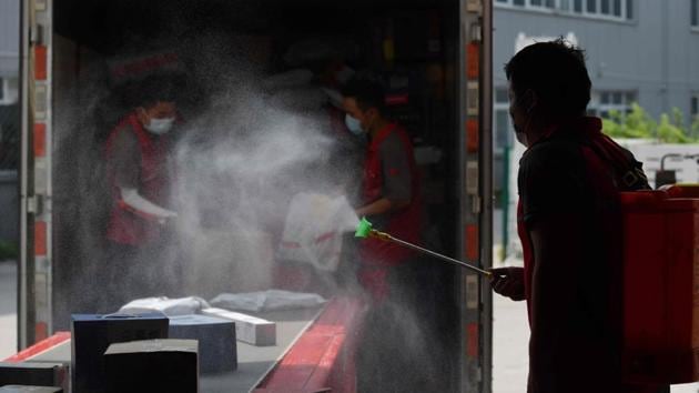 A worker disinfects packages as they are unloaded from a truck at a JD.com distribution center in Beijing on July 16. Economists say China is likely to recover faster than some other major economies due to Beijing’s decision to impose the most intensive anti-disease measures in history. That included stringent suspensions of trade and travel. (Greg Baker / AFP) A worker disinfects packages as they are unloaded from a truck at a JD.com distribution center in Beijing on July 16. Economists say China is likely to recover faster than some other major economies due to Beijing’s decision to impose the most intensive anti-disease measures in history. That included stringent suspensions of trade and travel. (Greg Baker / AFP)