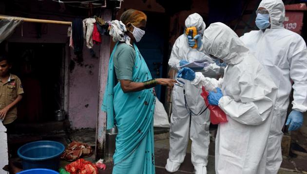 A BMC health care worker checks the temperature of the resident at Dharavi during Covid-19 pandemic in Mumbai on Thursday.(Satish Bate/HT Photo)