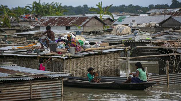 A flood affected family takes shelter on the roof of their partially submerged house in Morigaon district, Assam on July 16. The total number of people killed in flood related incidents in the state this year has gone up to 102. While 76 people have died due to the deluge, 26 others have been killed in landslides, PTI reported. (Anupam Nath / AP)