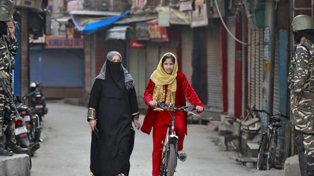 A Kashmir girl rides her bike past Indian security force personnel standing guard in front closed shops in a street in Srinagar. (Reuters File Photo) A Kashmir girl rides her bike past Indian security force personnel standing guard in front closed shops in a street in Srinagar. (Reuters File Photo)