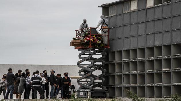 Cemetery workers in protective suits use a lift to carry out a wall crypt burial as family members look on at the Caju cemetery in Rio de Janeiro on July 16. “People have become callous,” Mandetta said. “When you say, ‘Yesterday there were 1,300 deaths,’ people say, ‘OK, then it didn’t go up. It was 1,300 people the day before, too.’” (Luis Alvarenga / Getty Images)