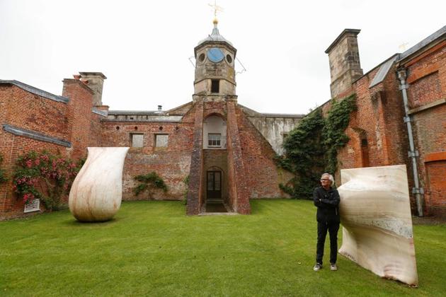 British-Indian artist Anish Kapoor poses with his sculptures in the gardens at Houghton Hall in Norfolk, Britain July 9, 2020. Kapoor’s exhibition of 24 sculptures was due go on show throughout the grounds and historic interiors of the hall in Norfolk, eastern England, in March but COVID-19 put paid to that plan. (REUTERS)
