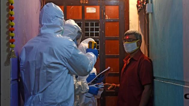 Health workers thermal screen a resident in Dharavi during door to door testing in Mumbai on July 17. Mumbai crossed the one-lakh cases mark, with the addition of 1,186 cases on July 18. The city’s Covid-19 tally now stands at 100,350 according to state health department data. (Vijayanand Gupta / HT Photo)