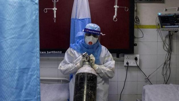 A medical worker wearing personal protective equipment (PPE) pushes an oxygen cylinder for a patient suffering from the coronavirus disease (COVID-19) at the casualty ward in Lok Nayak Jai Prakash (LNJP) hospital, in New Delhi.(REUTERS)