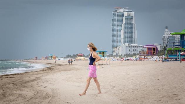A woman wearing a face mask walks towards the water at a beach in Miami, US on July 17. The United States, with more than 3.6 million confirmed cases as of July 18, is still seeing huge daily jumps in its first wave of COVID-19 infections. (Jayme Gershen / Bloomberg) A woman wearing a face mask walks towards the water at a beach in Miami, US on July 17. The United States, with more than 3.6 million confirmed cases as of July 18, is still seeing huge daily jumps in its first wave of COVID-19 infections. (Jayme Gershen / Bloomberg)