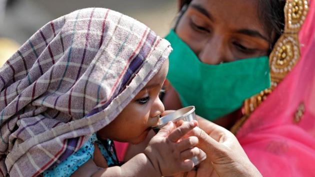 A child of a migrant worker drinks water as his mother holds him while waiting in a queue for transport to reach to a railway station to board a train to Uttar Pradesh, India. (REUTERS) A child of a migrant worker drinks water as his mother holds him while waiting in a queue for transport to reach to a railway station to board a train to Uttar Pradesh, India. (REUTERS)