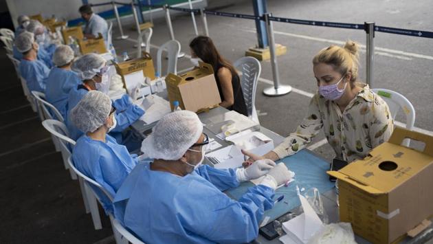 Health workers take residents' blood samples at a testing site for COVID-19 in Rio de Janeiro on July 17. Over the last two months, Brazil has recorded more than 30,000 new cases in a day 26 times, and on 11 of those occasions there were more than 40,000 infections, AFP reported. (Silvia Izquierdo / AP)