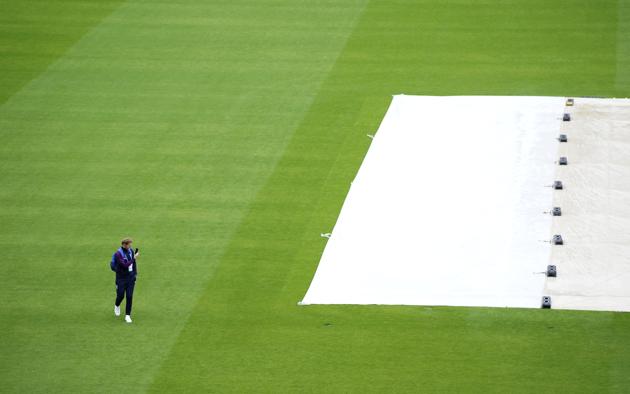England's Ben Stokes holds his mobile phone as he walks past the covered pitch area after rain delayed start of the third day of the second cricket Test match between England and West Indies at Old Trafford in Manchester, England, Saturday, July 18, 2020. (AP Photo/Jon Super, Pool) (AP)