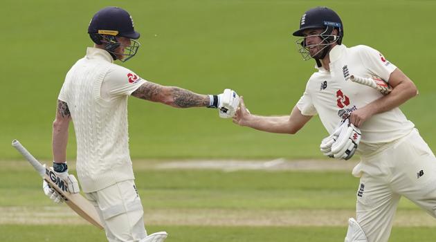 England's Ben Stokes, left, fist bumps teammate Dom Sibley to celebrate scoring 150 runs during the second day of the second cricket Test match between England and West Indies at Old Trafford in Manchester, England, Friday, July 17, 2020. (AP Photo/Jon Super, Pool) (AP)