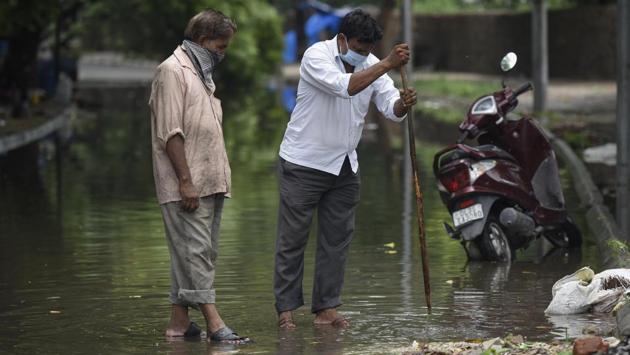 A man tries to unclog a drain after a road was waterlogged following heavy rain in Nizamuddin on July 19. The IMD said that Ridge, Lodhi Road, Palam and Ayanagar weather stations recorded 86 mm, 81.2mm, 16.9mm and 12.2mm rainfall, respectively. (Biplov Bhuyan / HT Photo)