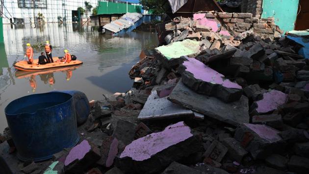 National Disaster Response Force (NDRF) personnel inspect an area on a dinghy where houses collapsed into a canal due to heavy rains in New Delhi on July 19. According to IMD, Delhi has recorded 47.9mm rainfall so far in July, which is 56% less than the normal of 109.4mm. (Sajjad Hussain / AFP)