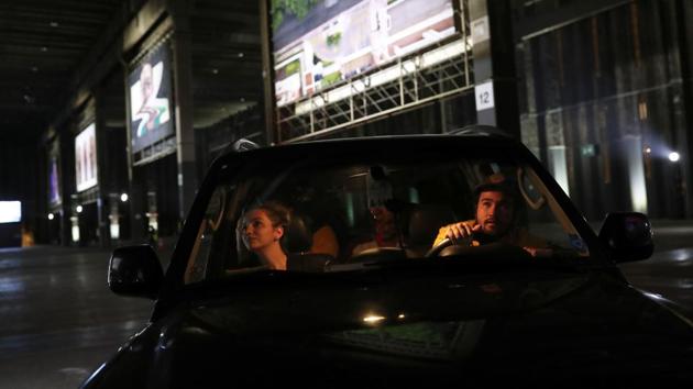 People look at an art piece from inside a car as they visit a drive-through art exhibition amid the coronavirus disease. (REUTERS/Amanda Perobelli)