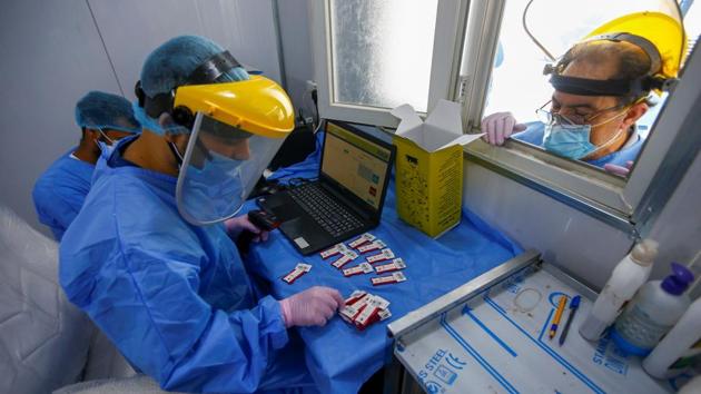 A healthcare worker checks blood samples collected from passengers at a coronavirus disease (COVID-19) drive-thru testing center in the holy city of Najaf, Iraq.(REUTERS)