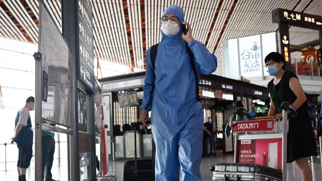 File photo: A man wearing a protective suit uses his phone at Beijing's international airport.(AFP)