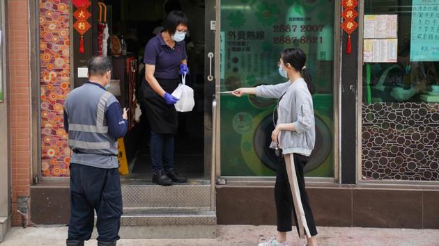 A staff member wearing a face mask hands takeaway food to a customer outside a restaurant in Hong Kong on July 20. Amusement parks, gyms and 10 other types of venues will remain closed through the week, while a requirement for restaurants to only provide takeaway after 6pm has been extended. (Lam Yik / REUTERS) A staff member wearing a face mask hands takeaway food to a customer outside a restaurant in Hong Kong on July 20. Amusement parks, gyms and 10 other types of venues will remain closed through the week, while a requirement for restaurants to only provide takeaway after 6pm has been extended. (Lam Yik / REUTERS)