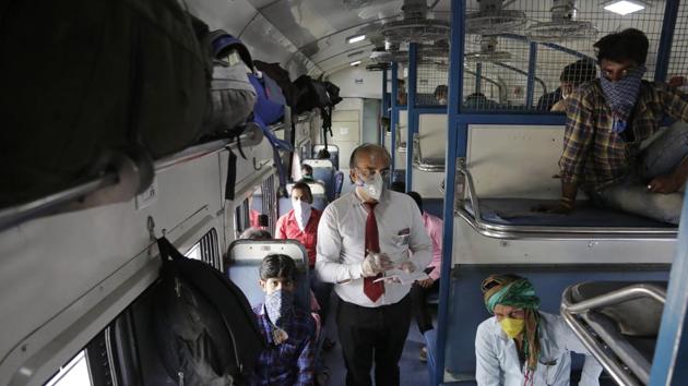 A ticket collector checks the tickets of migrant workers siting inside a special train to return to Agra in Uttar Pradesh state.(AP) A ticket collector checks the tickets of migrant workers siting inside a special train to return to Agra in Uttar Pradesh state.(AP)