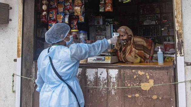 A health worker thermal screens a shopkeeper during door to door survey for coronavirus in a slum at Wadgaon Budruk in Pune, India, on Monday, July 6, 2020. (Pratham Gokhale/HT Photo) A health worker thermal screens a shopkeeper during door to door survey for coronavirus in a slum at Wadgaon Budruk in Pune, India, on Monday, July 6, 2020. (Pratham Gokhale/HT Photo)