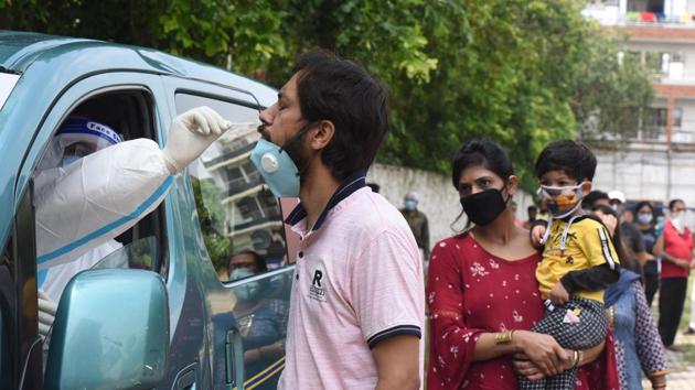 A health worker collects a swab sample from a man as others queue up for Covid-19 tests at Ramlila Maidan, New Delhi on July 21. According to the Union Health Ministry’s data from a sero-prevalence survey released on July 20, as much as 23.48% of Delhi’s population - 4.7 million people have been exposed to the virus that causes coronavirus (Covid-19) disease, HT reported. (Sonu Mehta / HT Photo)