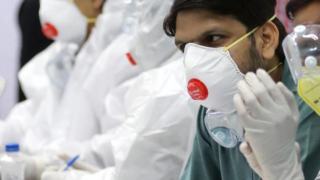 Health care workers wearing N95 respirators speak to a passenger recently arrived on a repatriation flight from Singapore at the Indira Gandhi International Airport in New Delhi.(Bloomberg)