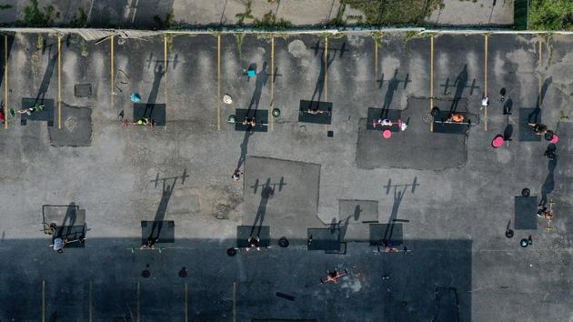 An aerial view of Fitness Instructor Dennis Guerrero (C) leading an outdoor Jetty Gym "Outside The Box" fitness workout on July 20 in Oceanside, New York. The number of positive Covid-19 cases and virus-related deaths remain low in New York at the moment. Of the nearly 50,000 tests conducted statewide on July 19, about 1.05% were positive, and there were eight virus-related deaths. (Al Bello / Getty Images / AFP)