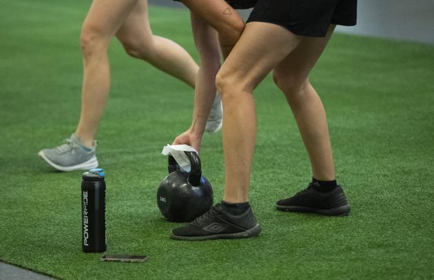 A members wipes down a kettlebell at a GoodLife Fitness Centers Inc. gym on its first day of reopening in Ottawa, Ontario, Canada, on Friday, July 17, 2020. Twenty-four districts, including Ottawa and Waterloo, are moving into the final stage of the three-part reopening plan as Covid-19 infections continue to drop. (Bloomberg)
