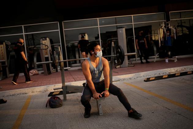 A man pauses his exercise routine at the parking lot of a gym, where its fitness equipment was temporarily moved, as the government has not announced a reopening date for fitness centers, during the coronavirus disease (COVID-19) outbreak, in Ciudad Juarez, Mexico July 15, 2020. (via REUTERS)