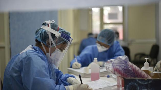 Medics in PPE suits complete paperwork at a coronavirus test desk at Delhi’s Lok Nayak jai Prakash (LNJP) Hospital.(Vipin Kumar/HT PHOTO)