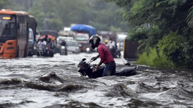 A motorist pushes his vehicle along a waterlogged road near Indraprastha after a heavy downpour in New Delhi on July 22. Delhi once again recorded “heavy” category rain after it poured in many parts of the city on July 22 morning. (Sanjeev Verma / HT Photo)