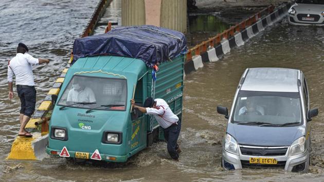 Traffic police personnel try to facilitate traffic movement on a waterlogged road at AIIMS in New Delhi on July 22. According to PWD and the civic bodies, at least 63 places in the city reported waterlogging on July 22, HT reported. (Biplov Bhuyan / HT Photo)
