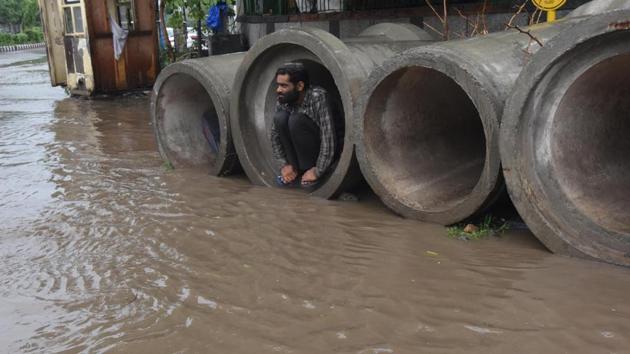 A man takes shelter inside concrete pipes assembled for construction purposes amid heavy rain at Mother Dairy Chowk in New Delhi on July 22. Delhi in the last four days alone has recorded 120mm of rain. Till July 19, Delhi had a rainfall deficit of 47%, which went down to 29% till July 21. (Raj K Raj / HT Photo)