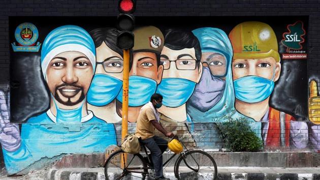 A man rides his bicycle past a graffiti, amidst the spread of the coronavirus disease (COVID-19), in New Delhi.(Reuters)