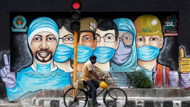 A man rides his bicycle past a graffiti, amidst the spread of the coronavirus disease in New Delhi. (REUTERS) A man rides his bicycle past a graffiti, amidst the spread of the coronavirus disease in New Delhi. (REUTERS)
