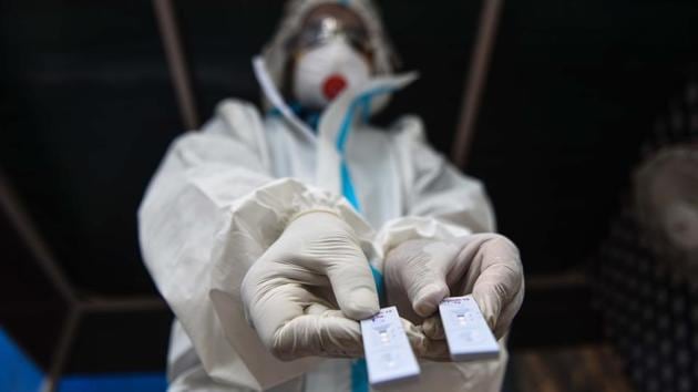 A health worker wearing PPE coveralls holds out Rapid Antigen test kits before preparing to collect swab samples to test for coronavirus, near Minto Bridge in New Delhi.(Sanchit Khanna/HT PHOTO/For Representative Purposes Only) A health worker wearing PPE coveralls holds out Rapid Antigen test kits before preparing to collect swab samples to test for coronavirus, near Minto Bridge in New Delhi.(Sanchit Khanna/HT PHOTO/For Representative Purposes Only)