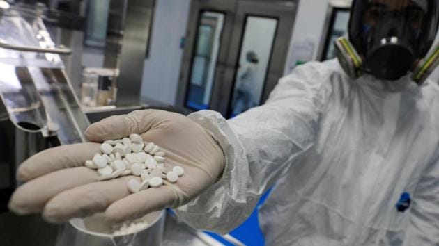 A lab technician wearing a full-face mask and a protective suit holds tablets of investigational coronavirus disease (Covid-19) treatment drug Favipiravir.(REUTERS/ For Representative Purposes Only)