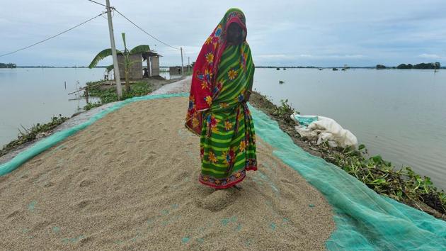 A woman spreads rice for drying on an embankment in a flooded area in Morigaon district on July 20. At present, 2,525 villages are under water and 1,15,515.25 hectares of crop areas have been damaged across Assam, the ASDMA told PTI. (David Talukdar / REUTERS)