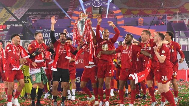 Liverpool players and staff celebrate with the trophy after winning the Premier League. (Pool via REUTERS)