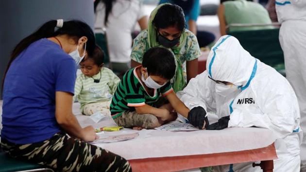 A medical worker helps a boy to draw inside a care centre for the coronavirus disease (Covid-19) patients at an indoor sports complex in New Delhi,on July 20. (Reuters Photo) A medical worker helps a boy to draw inside a care centre for the coronavirus disease (Covid-19) patients at an indoor sports complex in New Delhi,on July 20. (Reuters Photo)