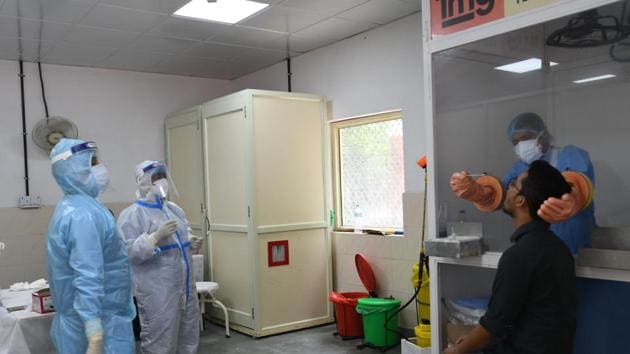 Health workers in PPE suits take a man’s swab sample for a coronavirus test, at Lok Nayak Jai Prakash (LNJP) Hospital, in New Delhi.(Vipin Kumar/HT PHOTO)