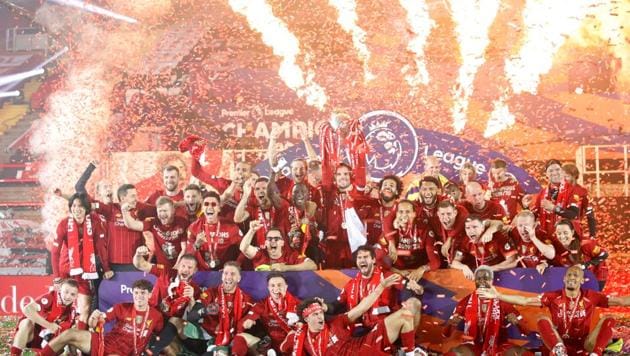 Liverpool's Jordan Henderson with teammates celebrates with the trophy after winning the Premier League.(Pool via REUTERS) Liverpool's Jordan Henderson with teammates celebrates with the trophy after winning the Premier League.(Pool via REUTERS)