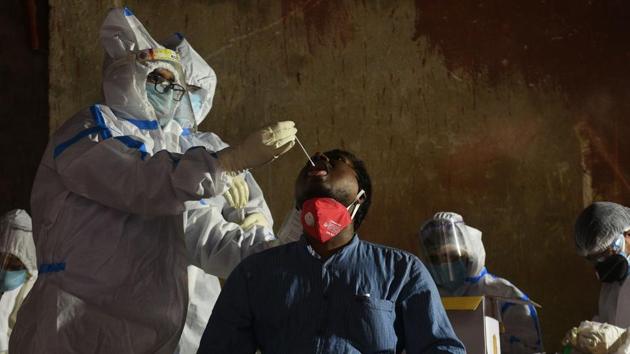 A medical professional in PPE coverall collects swab sample from a man to test for Covid-19 infection.(Samir Jana / Hindustan Times) A medical professional in PPE coverall collects swab sample from a man to test for Covid-19 infection.(Samir Jana / Hindustan Times)
