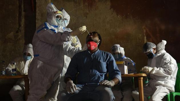 A medical professional in PPE coverall collects swab sample from a man to test for Covid-19 infection at KMC Ward No. 93 in Gobindapur, in Kolkata, West Bengal.(Samir Jana / Hindustan Times)