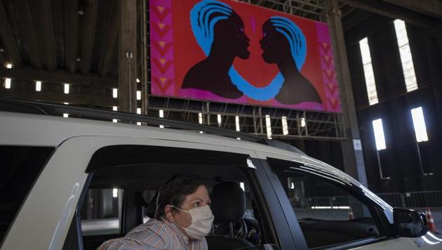 A woman takes in an art exhibit from the backseat of a car as she is driven through a warehouse displaying paintings and photos in Sao Paulo, Brazil, Friday, July 24, 2020, amid the new coronavirus pandemic. Galleries, cinemas, theaters and museums are closed due to the restrictive measures to avoid the spread of COVID-19, but a group of artists and a curator found a way to overcome the restrictions to share their art with the residents of Brazil’s largest city. (AP)
