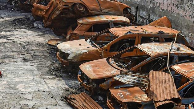 A man walks past the charred remains of vehicles set ablaze by rioters at parking during the anti-CAA protests in February, at Shiv Vihar area of Northeast Delhi.(PTI) A man walks past the charred remains of vehicles set ablaze by rioters at parking during the anti-CAA protests in February, at Shiv Vihar area of Northeast Delhi.(PTI)