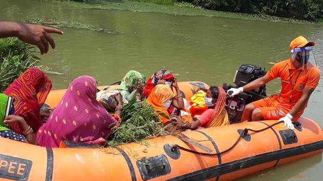 NDRF jawans helping flood affected people on a boat from flood area in Gopalganj, Bihar.(HT Photo)