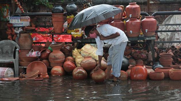 A potter grabs his earthen pitchers from getting swept away during rain on Ajmer road in Jaipur, Rajasthan on Saturday.(Himanshu Vyas/HT File Photo)