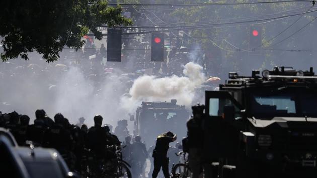 Police in riot gear faced off against the demonstrators, some of whom held up umbrellas against falling pellets of pepper spray.(AP Photo)