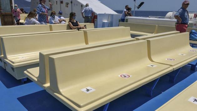 Signs on the seats of the ferry to Giglio island remember travelers to respect social distancing, Tuesday, June 23, 2020. (AP Photo/Paolo Santalucia)