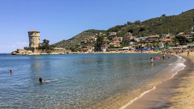 In this photo taken on Wednesday, June 24, 2020, people enjoy the sun and the fresh water on a beach at the Giglio island, in front of Tuscany, Italy. In spite of various people with coronavirus stopped by the island at times, no one of the islanders developed Covid-19 infection.(AP Photo/Paolo Santalucia)