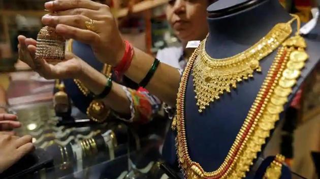 A saleswoman shows a gold earring to customers at a jewellery showroom in Mumbai.(Reuters File Photo)